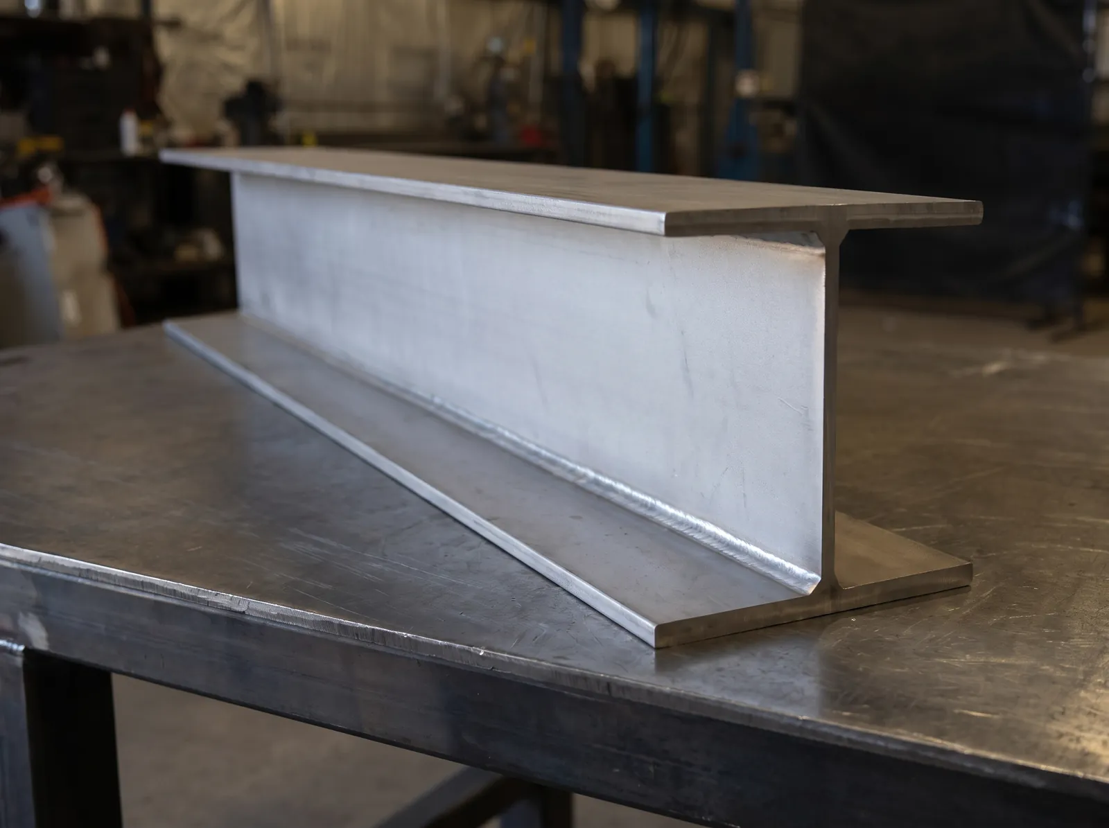 Stainless built-up I-beam on a steel work table: two flange plates and one web plate, fillet-welded, 316 mill finish