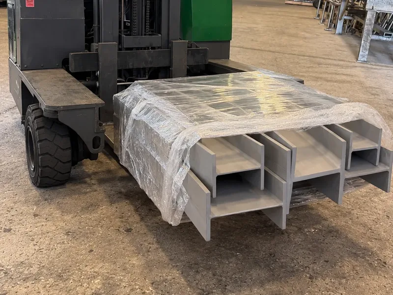 Finished stainless built-up beams, stretch-wrapped on a sideloader forklift, ready to ship